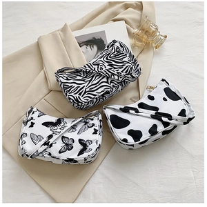 Detailed flat lay of three stylish underarm bags with zebra, butterfly, and cow patterns