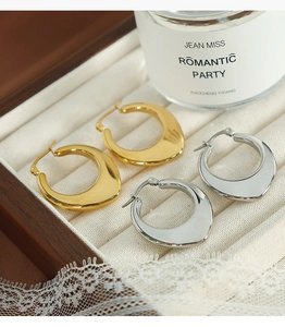 Polished gold and silver U-shaped hollow earrings displayed in a white velvet jewelry box