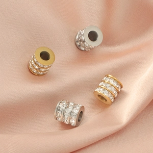 Cylindrical spacer beads in gold and silver with rhinestones on pink silk background