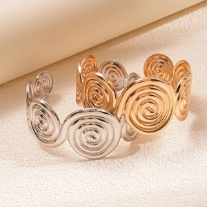 Detailed view of gold and silver spiral cuff bracelets with high polish textured finish