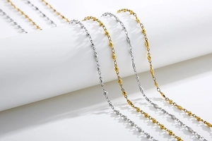 Dettaglio di catene minimaliste in acciaio al titanio oro e argento con perle e maglie