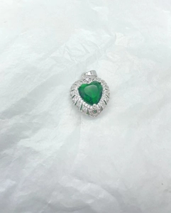 Detailed view of a silver heart pendant with a green center stone and clear zircons