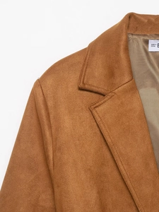 Detailed view of notch lapels and shoulder stitching on a camel faux suede blazer