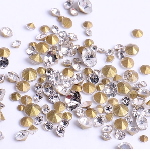 Macro shot of loose gold and clear pointed back rhinestones with multi-faceted cut detail