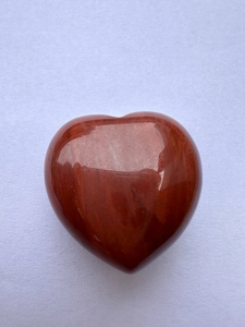 Macro detail of a 3cm heart-shaped red jasper natural stone with polished texture