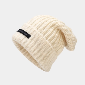 Gorro de punto grueso color crema para mujer con etiqueta negra de diseño minimalista