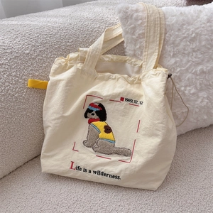 Detail of cute puppy embroidery and drawstring closure on beige canvas tote bag