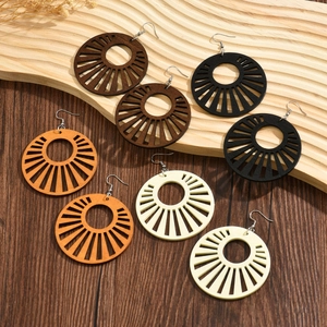 Four pairs of geometric hollow wooden earrings in assorted colors on a wooden surface