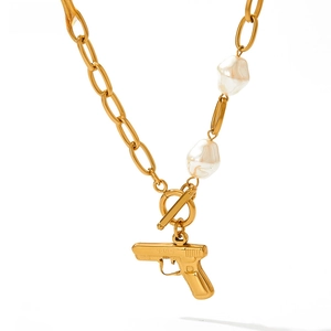 Detail of gold chain necklace featuring baroque pearls and a pistol-shaped pendant with OT buckle