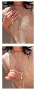 Detail of silver vintage sweater necklace with a pearl drop and colorful bell pendant