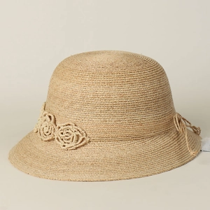 Close-up of hand-woven flower and ribbon detail on beige raffia straw sun hat