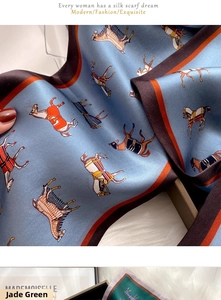 Close-up of light blue silk scarf featuring colorful horse prints and satin texture