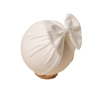 Elastic white ribbed knit baby turban hat featuring a large decorative bow on top