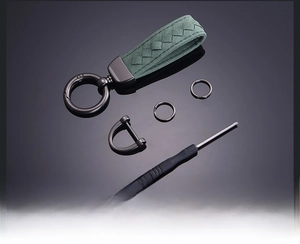 Close-up of dark green suede woven car keychain with hardware rings and screwdriver