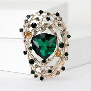 Detail view of bird's nest brooch with gold finish and green, yellow, clear crystals