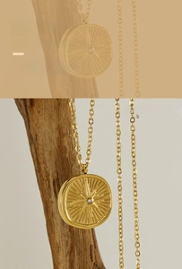Close-up of a gold stainless steel compass necklace with a sparkling diamond star pendant