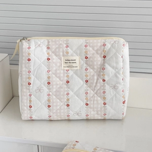 Detailed view of quilted makeup bag with pink floral patterns and secure metal zipper