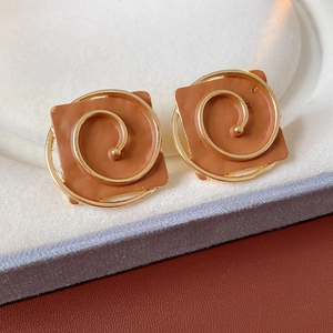 Macro detail of vintage brown square enamel earrings with golden spiral wire accents