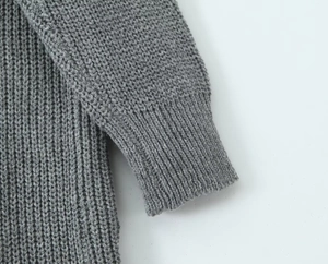 Detail of ribbed cuffs and thick knit texture on a long grey cardigan sweater