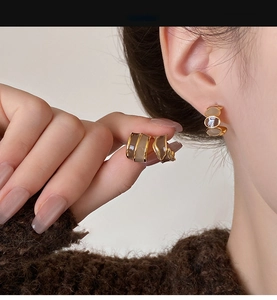 Close-up of elegant C-shaped Maillard brown earrings with gold metal accents worn by a model