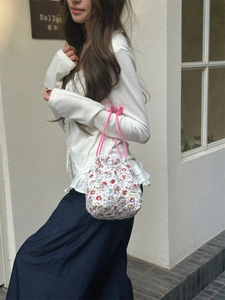 Close-up of quilted floral bucket bag with bear patterns and pink braided handles