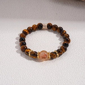 Macro shot of tiger eye stone beaded bracelet with gold metal spacers on gray surface