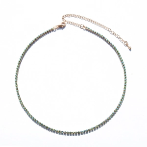Macro view of gold chain link necklace with vibrant green rhinestones and lobster clasp