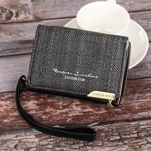 Close-up of herringbone texture on dark grey wallet with wrist strap on wooden surface