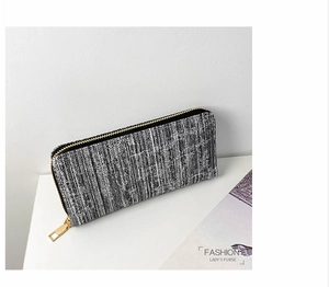 Detail of long striped fabric wallet featuring a golden zipper and premium texture