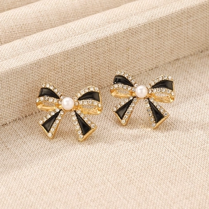 Detail of vintage French bow earrings with black enamel, white pearl and clear crystals