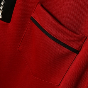 Detail of red pique fabric with black zipper placket and functional chest pocket