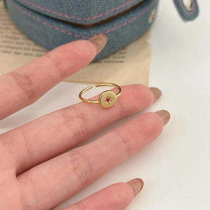 Detail of adjustable gold ring with red gemstone and etched star on blue denim fabric
