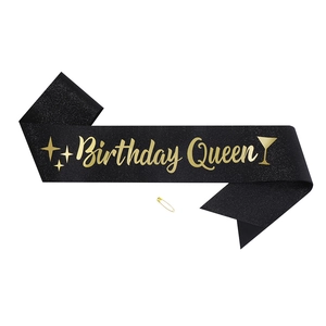 Detail of black glitter birthday queen sash with gold lettering and safety pin
