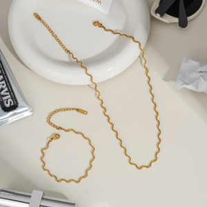 Macro detail of wave curved snake chain necklace and bracelet set in gold finish