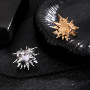 Detailed view of punk style spiked rings in gold and silver finish on black texture