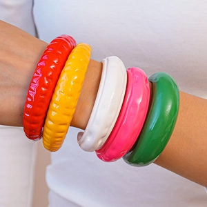 Dettaglio di bracciali in resina acrilica colorata con texture ondulata e finitura lucida