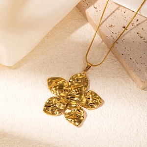 Detail of gold flower pendant necklace featuring a unique hammered metal texture finish