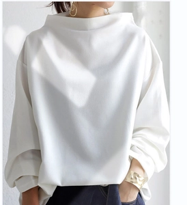 Detailed texture of white long sleeve blouse with elegant boat neck and loose knit fabric