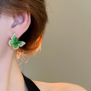 Detailed close-up of 18k gold plated butterfly stud earrings with green crystals