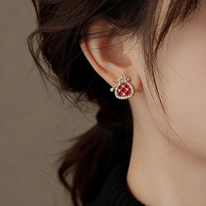 Macro detail of red fortune bag stud earring with gold plating and cubic zirconia