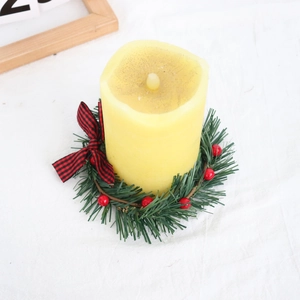Close-up of LED candle with Christmas wreath featuring pine needles and plaid bow