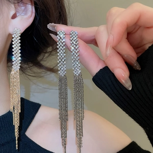 Detail of long tassel earrings with sparkling rhinestones in gold and silver finishes