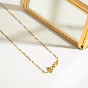Macro shot of 18K gold plated stainless steel necklace featuring a cursive Love pendant