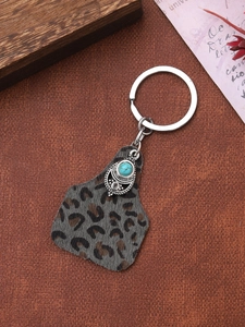 Detailed view of leopard print pendant keychain with turquoise stone and vintage metalwork