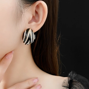 Close-up of vintage gold earrings with black enamel and sparkling rhinestones