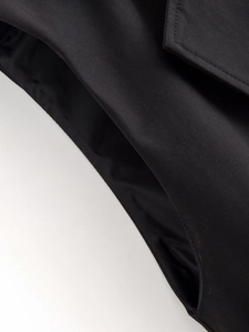 Détail macro du tissu sergé noir et des coutures de précision sur la veste