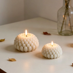 Due candele profumate a forma di ciottolo bianco in grandi e piccole con fiamma calda