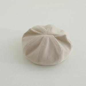 Close-up of beige knitted beret featuring detailed ribbed texture and soft fabric