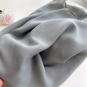 Close-up of grey cotton linen scarf fabric texture with soft drapes and rose petal detail