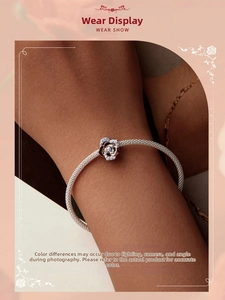 Detail of rose gold flower charm with pavé crystals on a silver mesh bracelet
